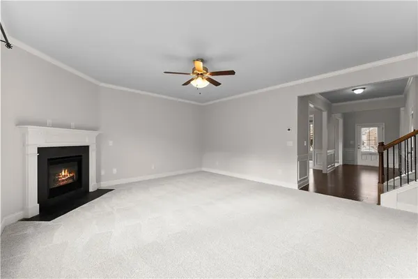 a view of an empty room with fireplace and a chandelier fan