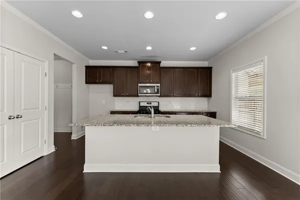 a large kitchen with stainless steel appliances granite countertop a sink a stove and a refrigerator