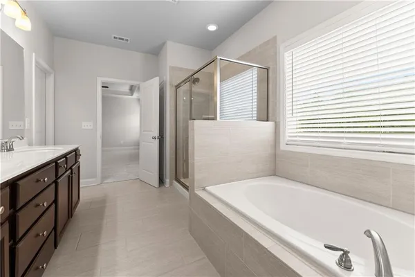 a spacious bathroom with a tub a sink and a large mirror