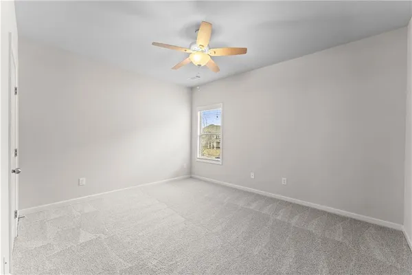 an empty room with a chandelier fan and window