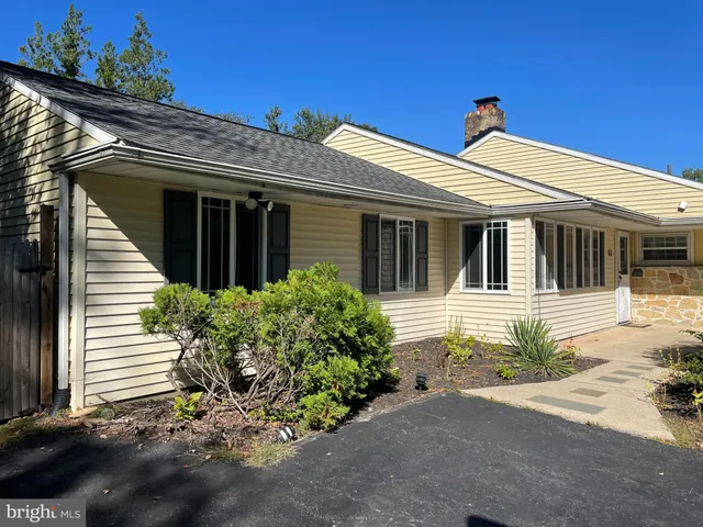 a view of a white house with large windows and flower plants