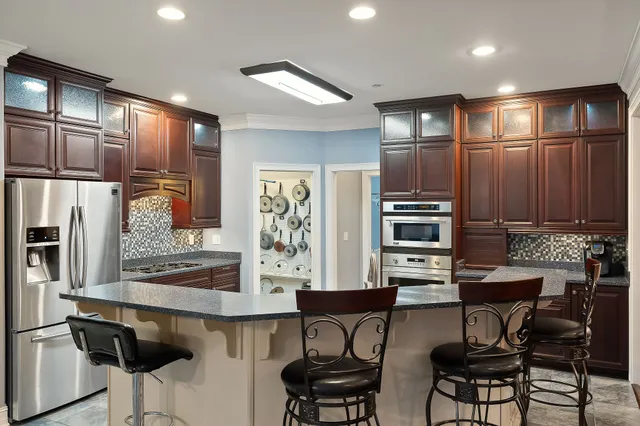 a kitchen with stainless steel appliances kitchen island granite countertop a table chairs in it and wooden floors