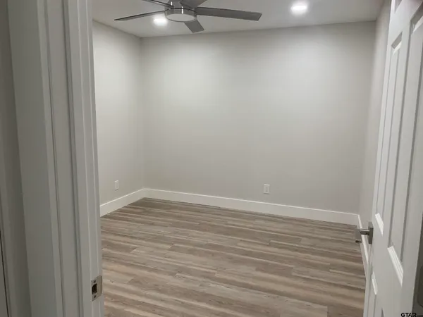 en empty room with wooden floor and fan
