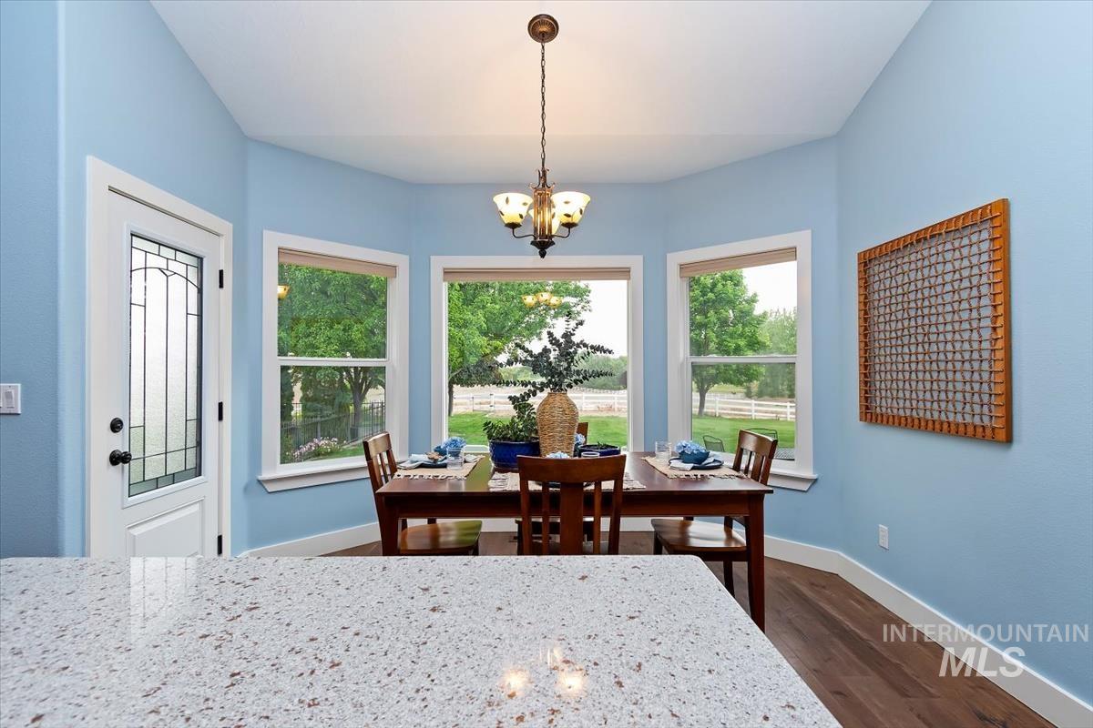 10462 West Lanktree Gulch Road Star, ID 83669 - Photo 12 of 48 Dining area featuring a bay window with three large windows, a decorative glass paneled door, and wood-finish flooring