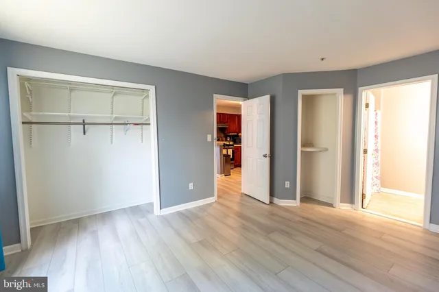 an empty room with wooden floor closet and windows