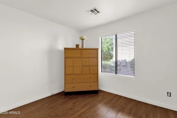 an empty room with wooden floor closet and windows