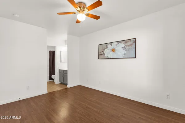 an empty room with wooden floor chandelier fan and windows