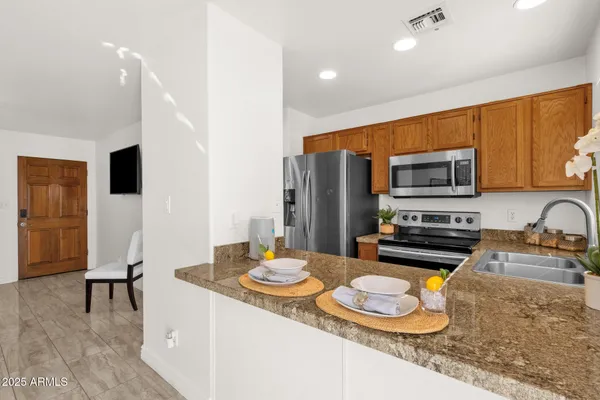 a kitchen with a sink a stove and chairs with wooden floor