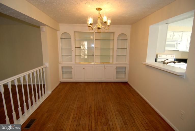 1489 Autumn Ridge Circle Reston, VA 20194 - Photo 7 of 23 a view of a hallway with wooden floor and chandelier