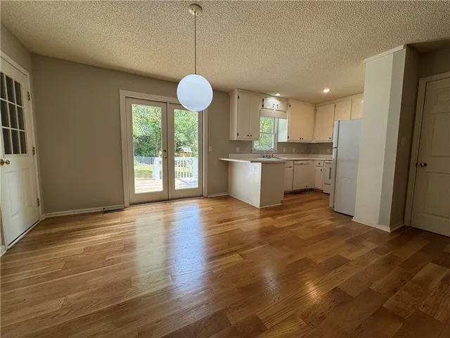 a open kitchen with stainless steel appliances granite countertop a sink a refrigerator and a wooden floor