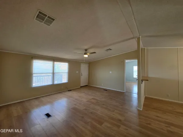 a view of an empty room with a window and wooden floor