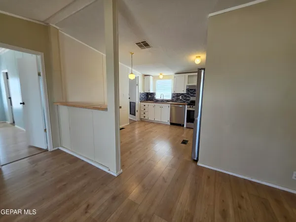 a view of an empty room with window and wooden floor