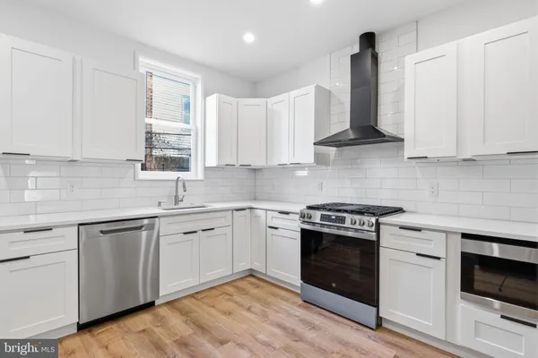 a kitchen with white cabinets appliances and a window