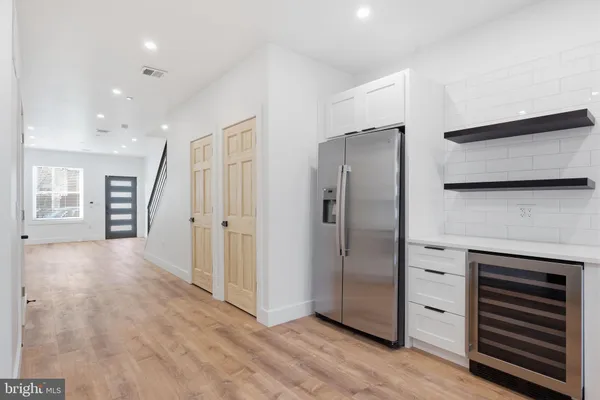 a view of an empty room with kitchen and a window