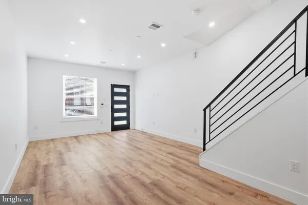 a view of an empty room with a window and wooden floor