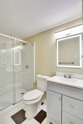 a bathroom with a toilet a sink a glass door a shower a mirror and vanity