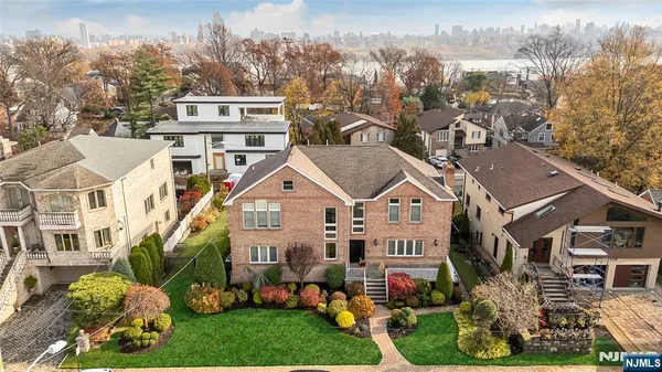 a view of a white house next to a yard with big trees
