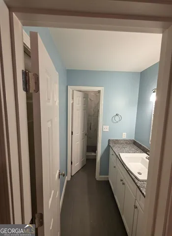 a bathroom with a granite countertop sink a mirror and a shower