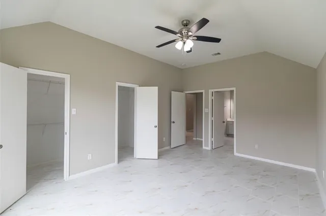an empty room with chandelier fan and windows
