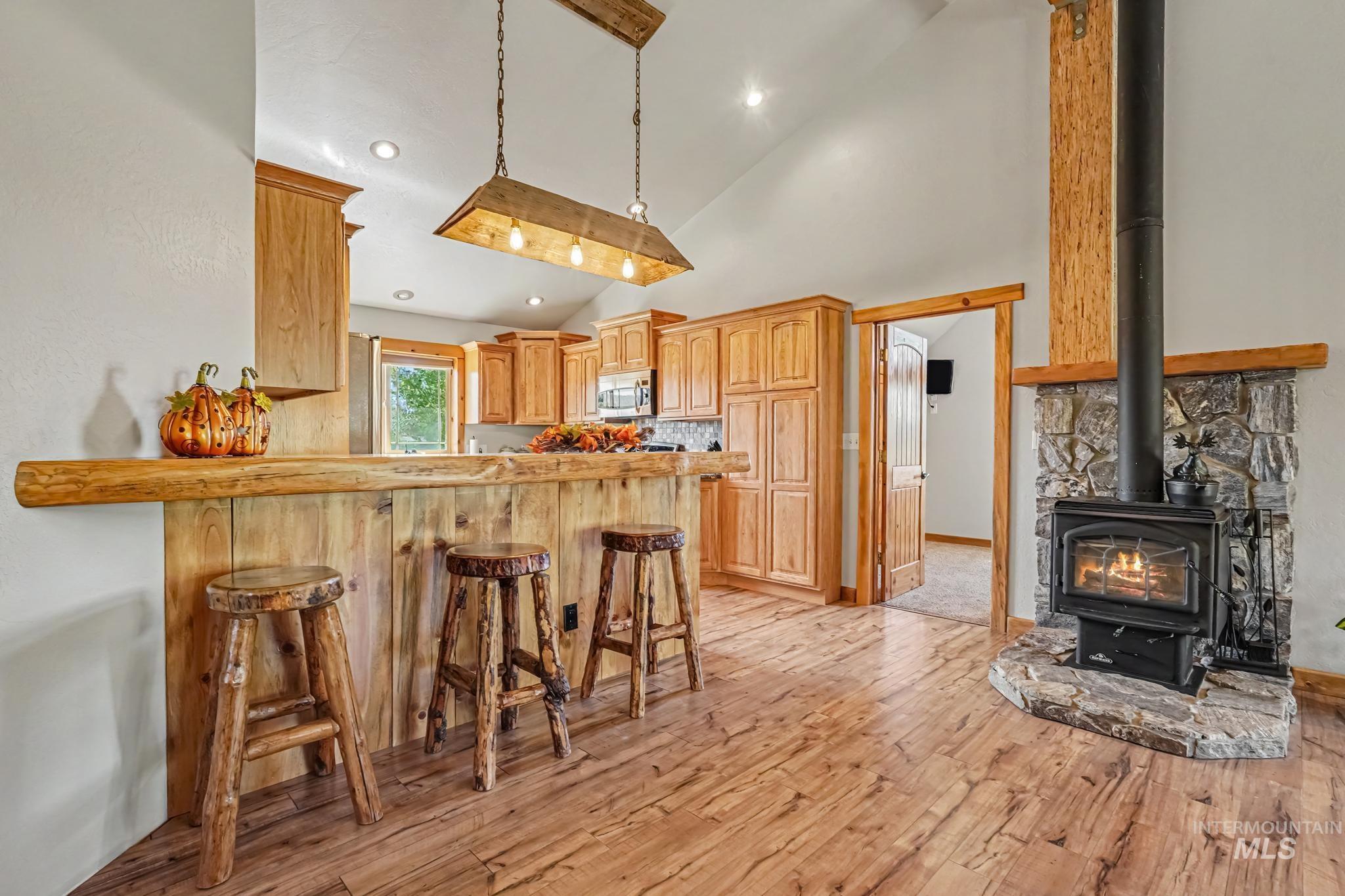 106 Wilderness Lake Road Cascade, ID 83611 - Photo 14 of 35 Vaulted ceiling, wood-finish flooring, stone fireplace with hearth, wood bar, and wood cabinetry