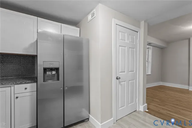 a view of a livingroom with wooden floor kitchen view and a refrigerator