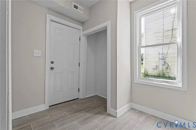 a view of an empty room with wooden floor and a window