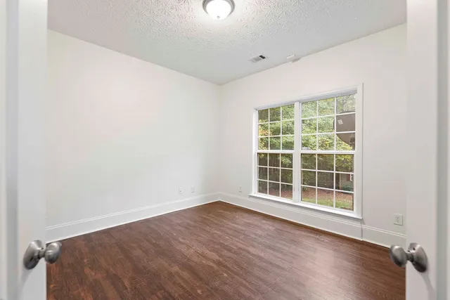 an empty room with wooden floor and windows