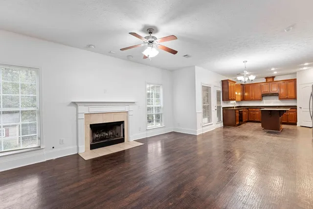 an empty room with wooden floor fireplace and windows