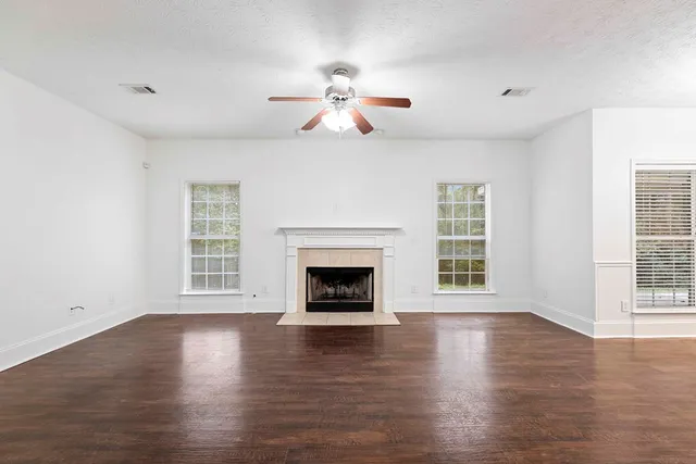 a view of an empty room with wooden floor fireplace and a window