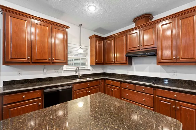 a kitchen with stainless steel appliances granite countertop wooden cabinets a refrigerator and sink