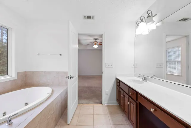 a spacious bathroom with a tub sink shower and mirror