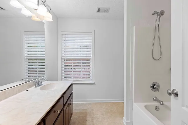 a bathroom with a granite countertop sink a mirror and a bathtub