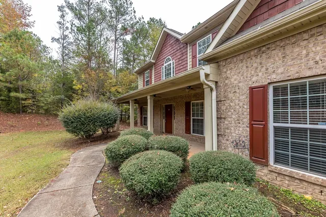 a view of a house with brick walls plants and large tree