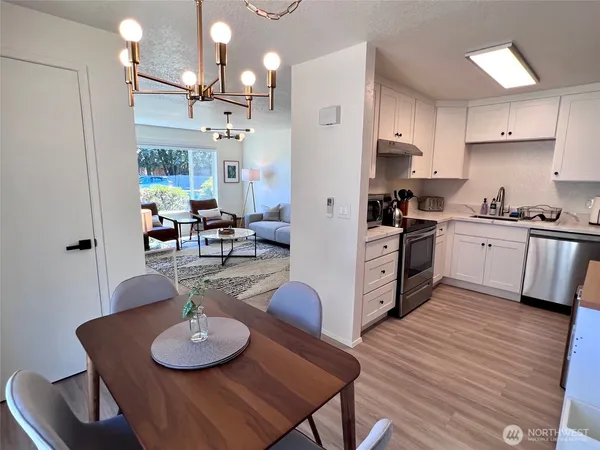 a kitchen with stainless steel appliances kitchen island granite countertop a table chairs stove and white cabinets