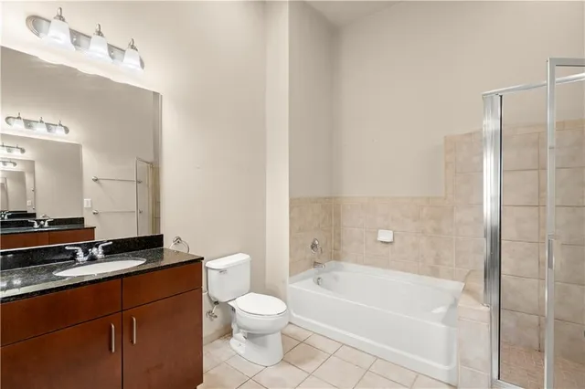 a bathroom with a granite countertop sink a toilet and bathtub