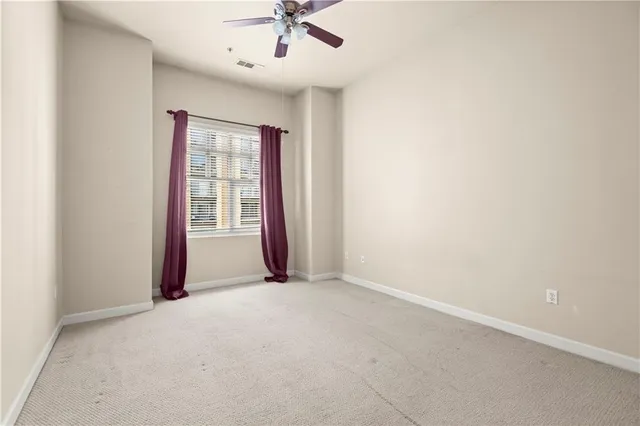 an empty room with a window and a ceiling fan