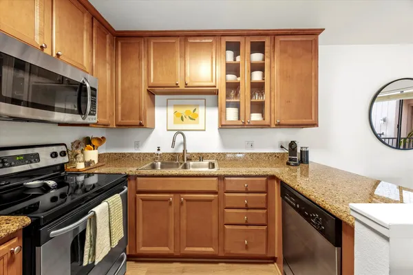 a kitchen with granite countertop stainless steel appliances a stove sink and cabinets