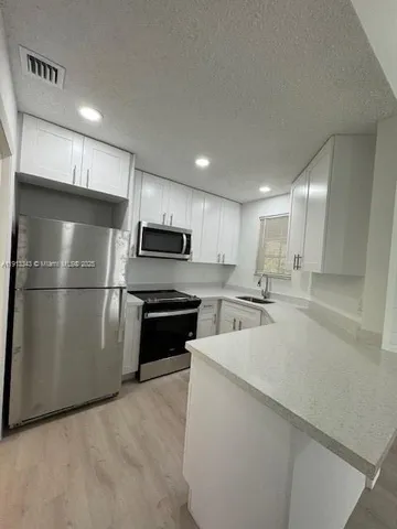 a kitchen with stainless steel appliances a refrigerator sink and microwave