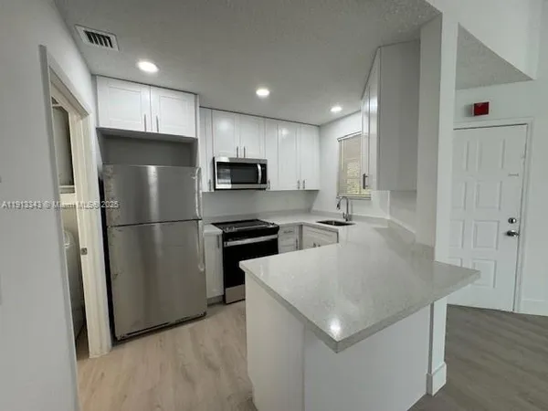 a kitchen with stainless steel appliances granite countertop a refrigerator a sink a stove a microwave and a refrigerator