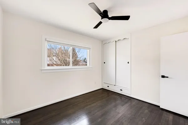 an empty room with wooden floor ceiling fan and windows