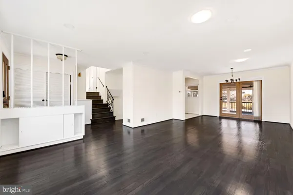 a view of an empty room with wooden floor and stairs