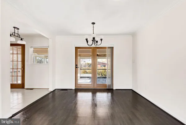 an empty room with wooden floor chandelier and windows