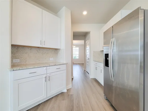 a kitchen with white cabinets and refrigerator
