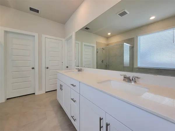 a spacious bathroom with a double vanity sink a mirror and a bathtub