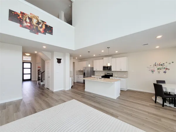 a living room with stainless steel appliances furniture and a wooden floor
