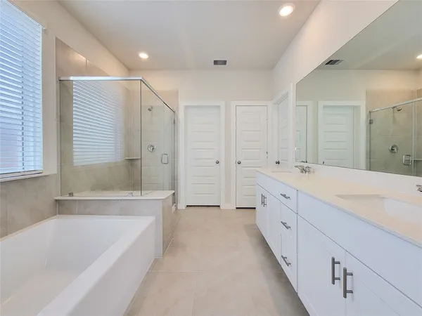 a spacious bathroom with a tub sink shower and mirror