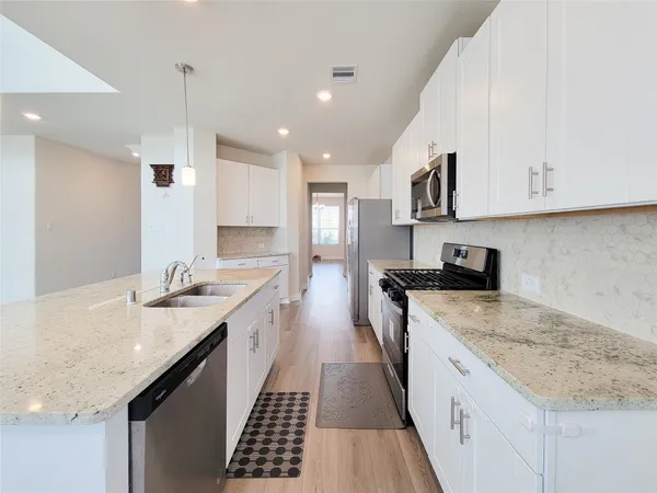 a large kitchen with stainless steel appliances granite countertop a sink stove and refrigerator