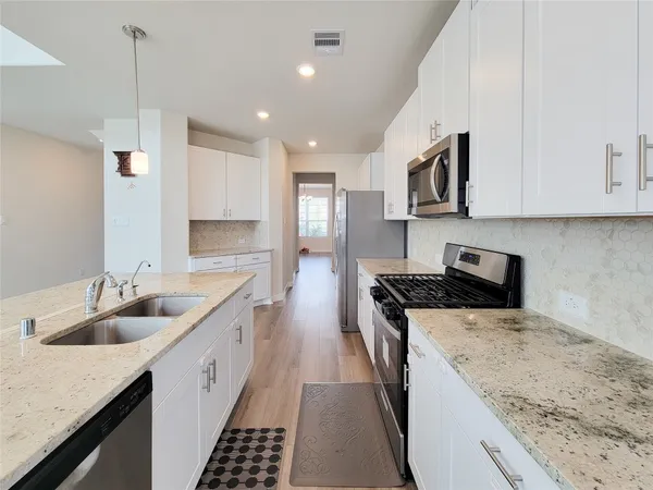 a kitchen with stainless steel appliances granite countertop a sink stove and cabinets