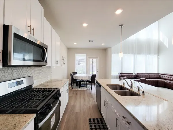 a kitchen with stainless steel appliances a sink a stove top oven a counter space and cabinets