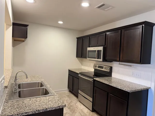 a kitchen with granite countertop stainless steel appliances and wooden cabinets